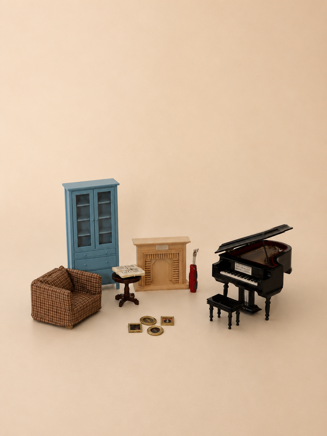A miniature dollhouse furniture set displayed on a warm beige background, including a black grand piano with bench, a blue cabinet, a brown armchair, a beige fireplace, and a small side table.