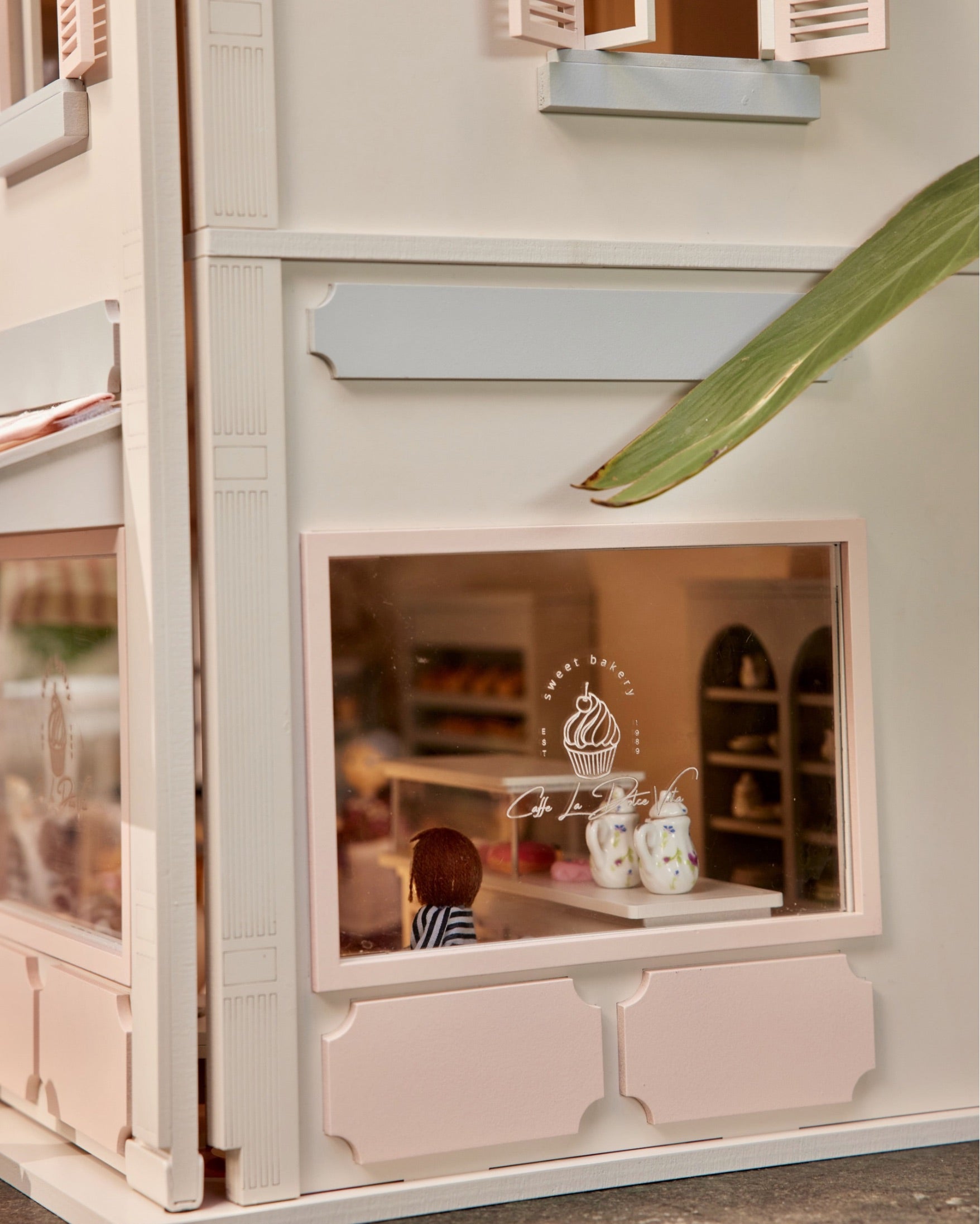 Shop window detail of the House of Rome dollhouse bakery with miniature pastries on display.