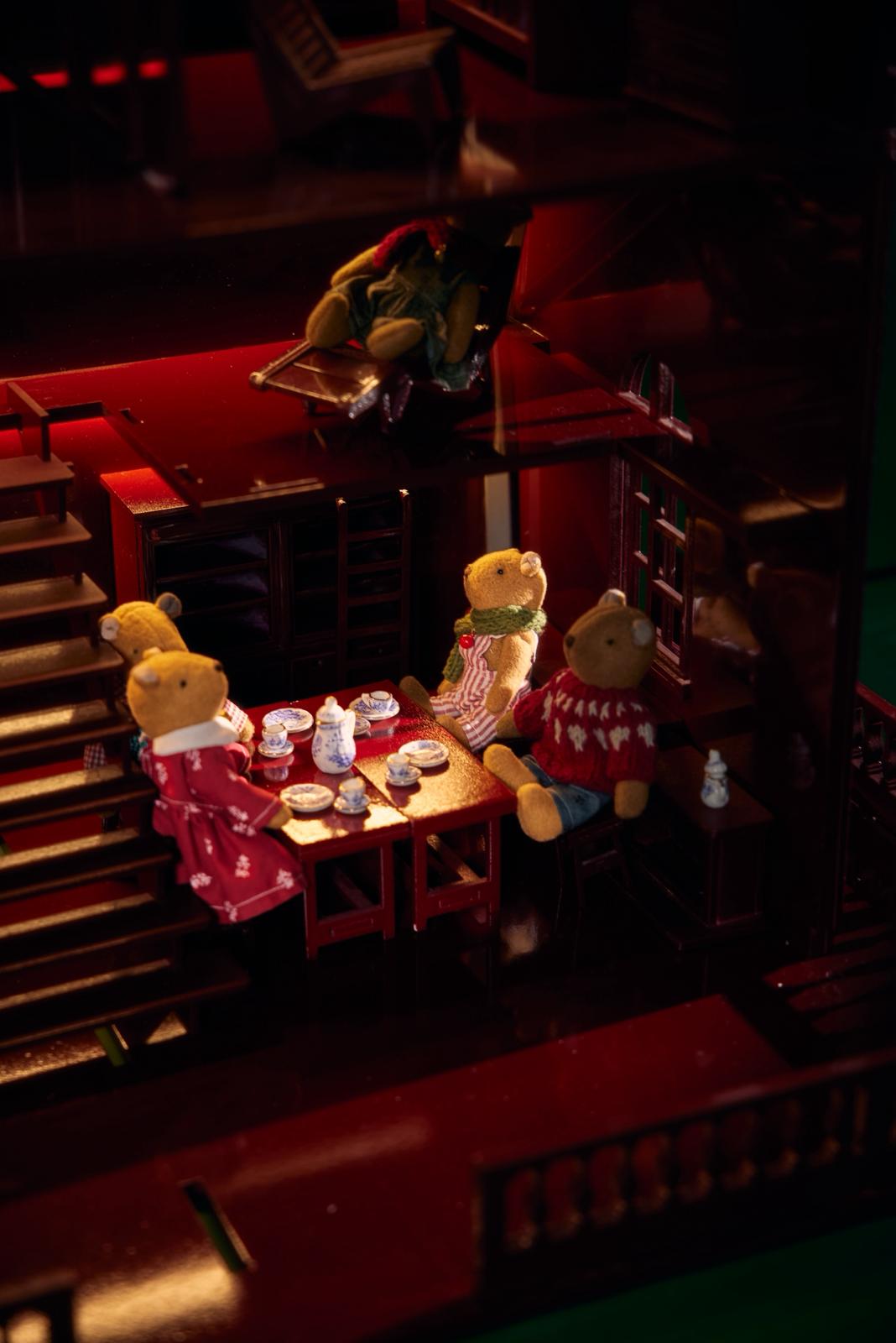 Teddy bears gathered around a Christmas dinner table inside the red wooden House of Bordeaux, handcrafted by Little Forest Animals, a limited-edition quiet luxury décor piece.