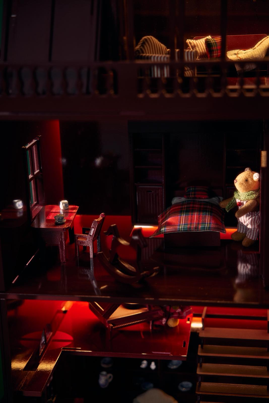 Elegant red wooden dollhouse glowing with soft light, a quiet luxury Christmas collectible handcrafted by Little Forest Animals, symbol of warmth and timeless beauty.