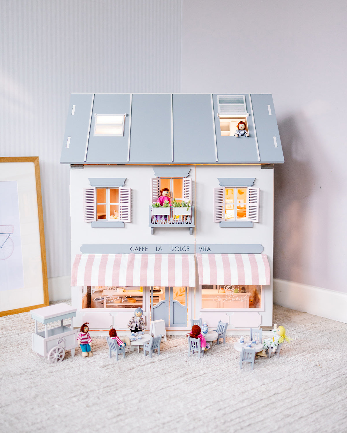 The House of Rome dollhouse featuring an Italian-style café, outdoor seating, and illuminated bakery windows.
