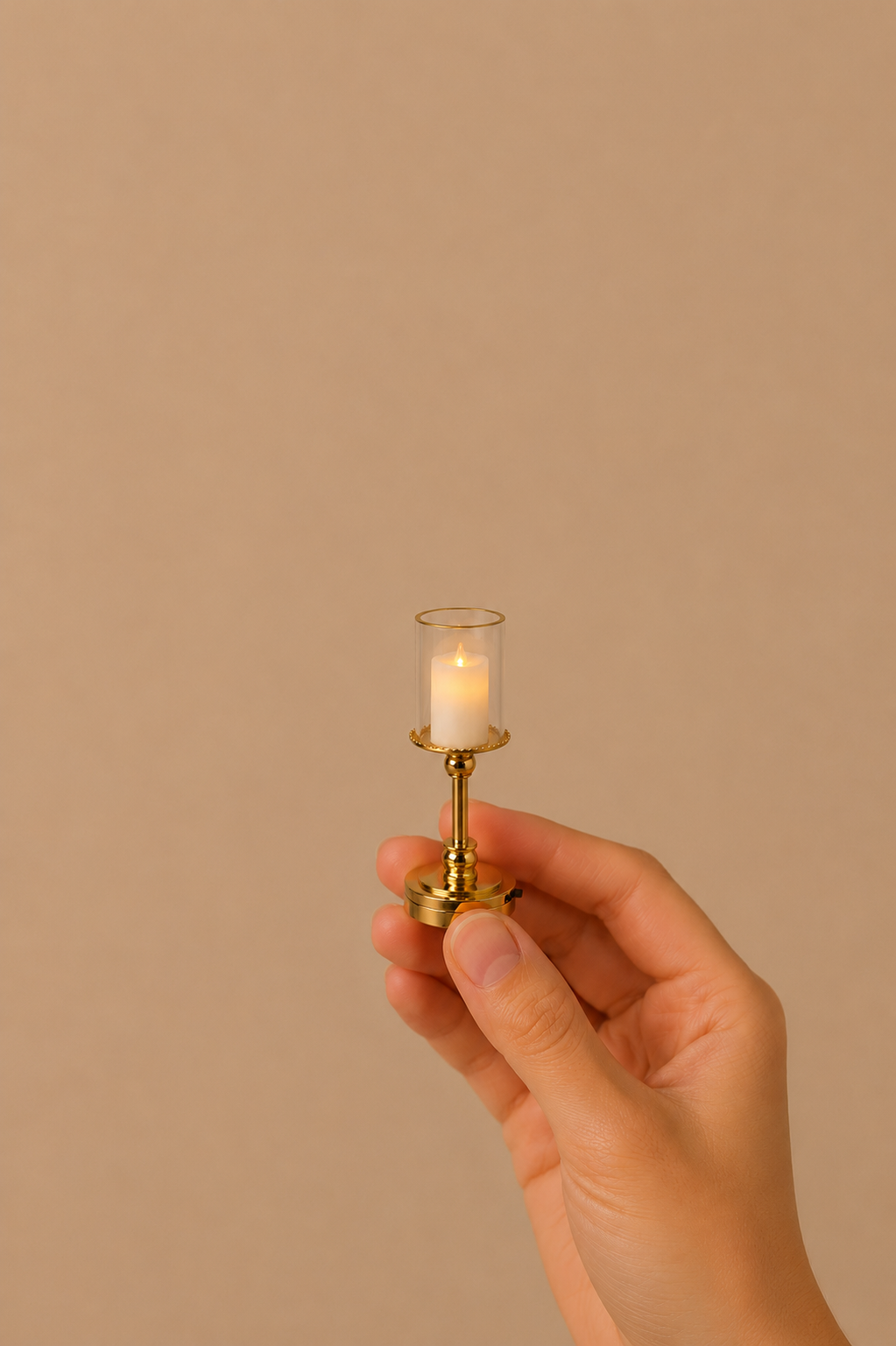 Miniature brass candle lamp with a lit LED candle held in a hand.