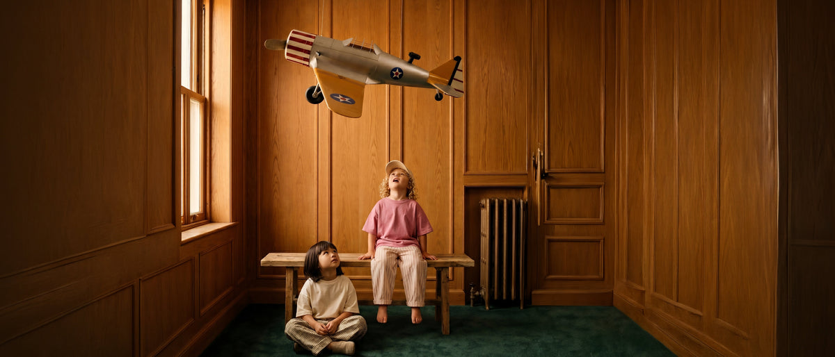 Two children looking up at The Hudson airplane hanging from the ceiling.