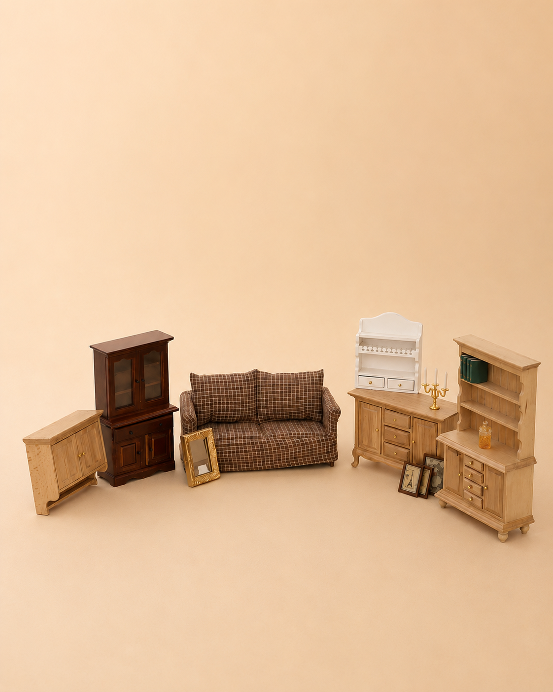 A miniature dollhouse furniture set arranged on a warm beige background, including a brown plaid sofa, a dark wood cabinet, light wood side tables, a white shelf, and a tall light wood bookcase.