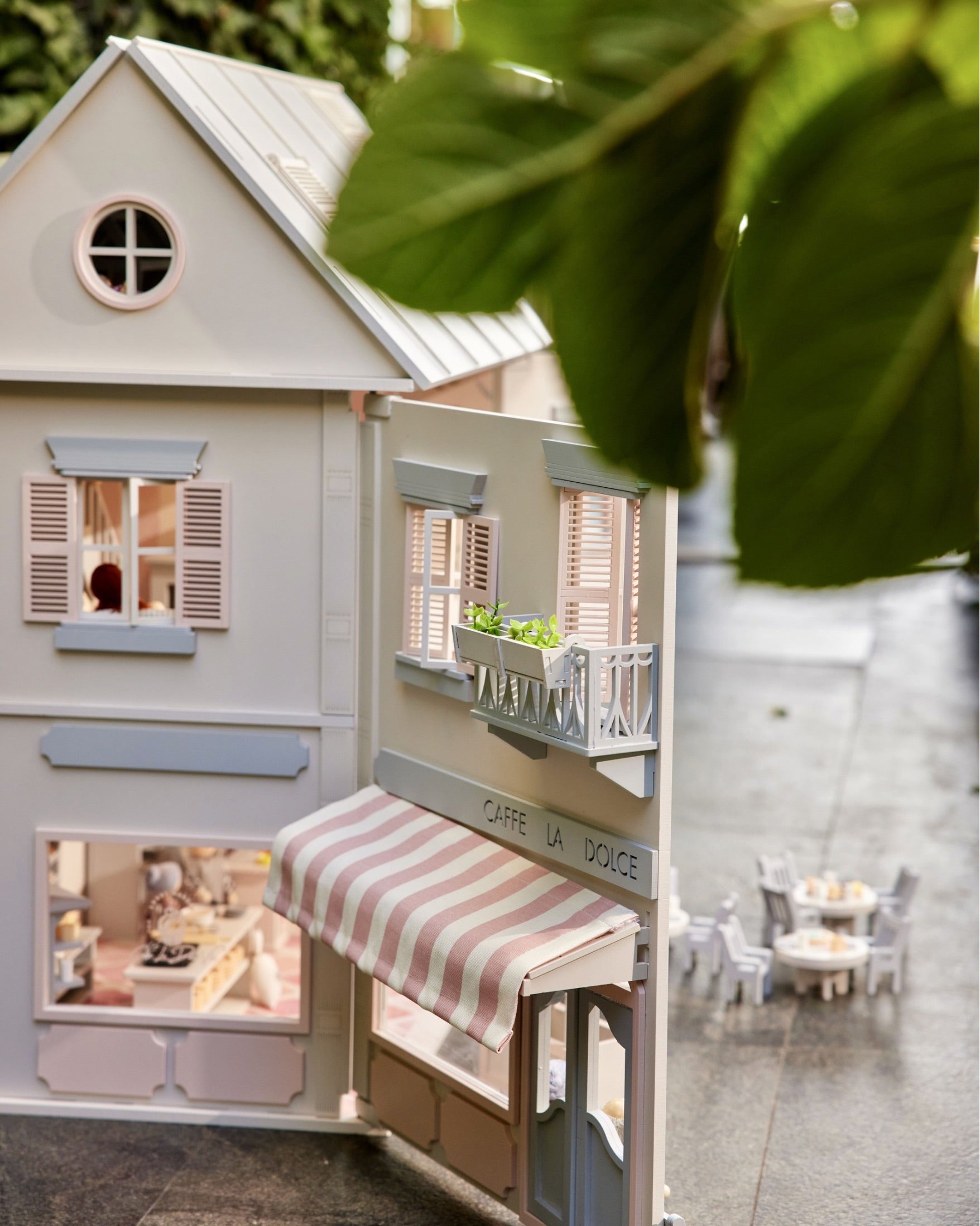 Close view of the House of Rome dollhouse café with awning and miniature outdoor tables.