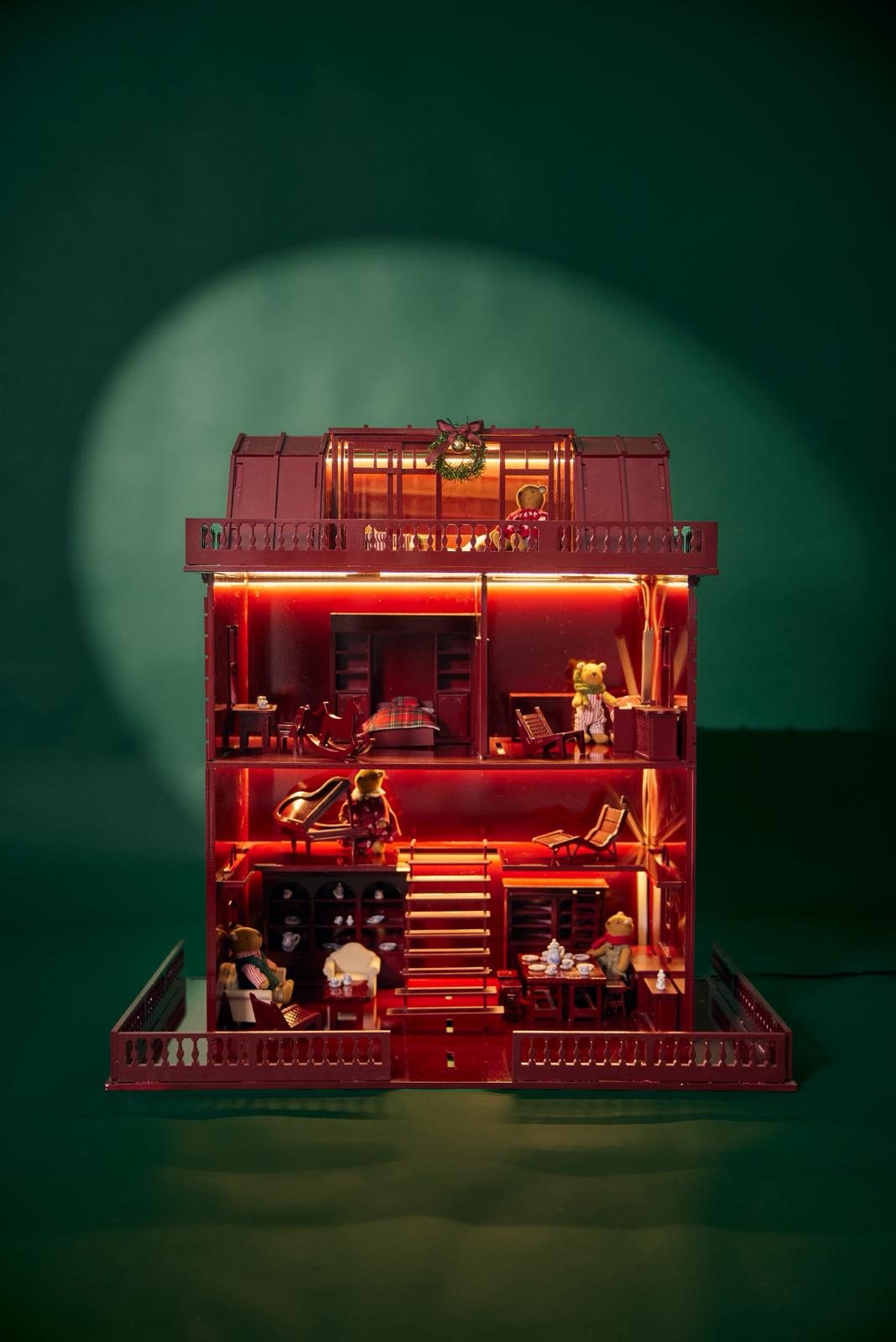 Red toy house with illuminated interior and bear figures