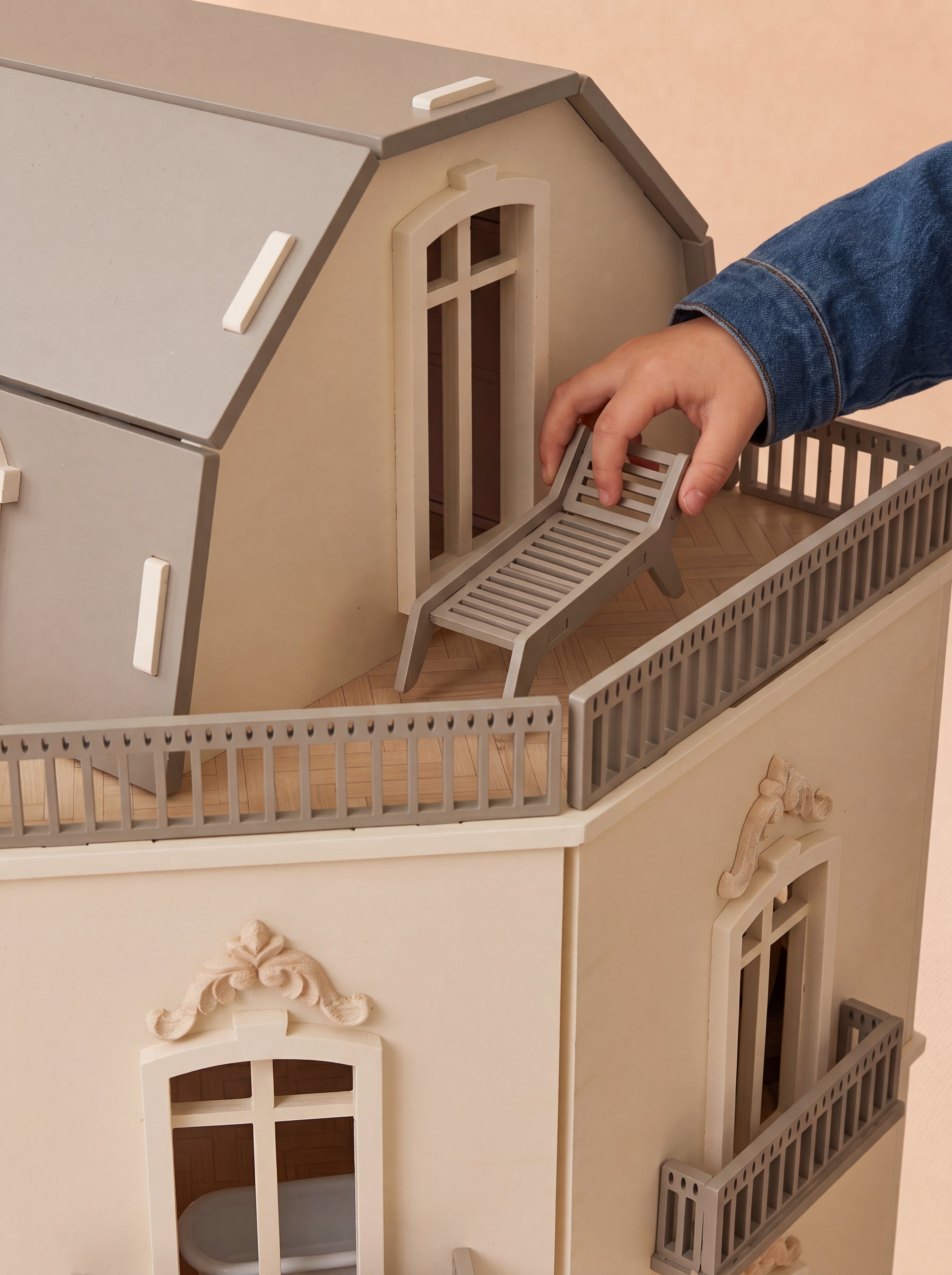 A lounge chair is placed on the rooftop terrace of the House of Paris dollhouse, highlighting the detailed outdoor space.