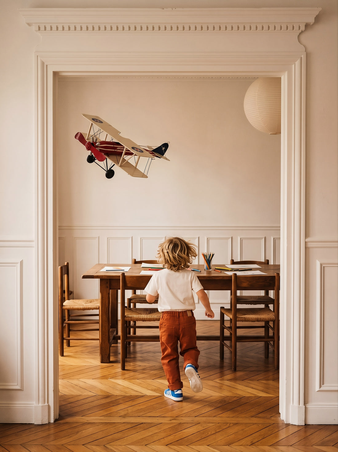A large vintage biplane hangs above a dining table as a child walks toward it.