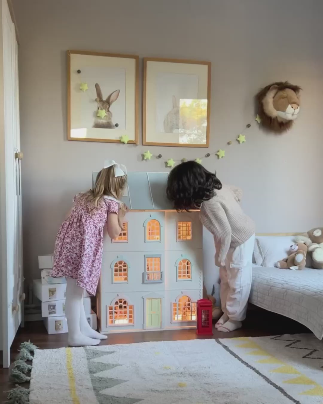 Children playing with the House of London wooden dollhouse, opening the front panels, exploring the furnished rooms, and turning on the warm interior lights.