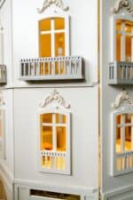 Front view of the handcrafted four-story Paris Dollhouse featuring French architectural details and miniature storefront windows.