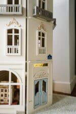Front view of the handcrafted four-story Paris Dollhouse featuring French architectural details and miniature storefront windows.