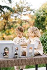 Miniature wooden flower shop dollhouse in pastel blue, with plants, a bunny figure, and charming outdoor details.