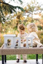 Miniature wooden flower shop dollhouse in pastel blue, with plants, a bunny figure, and charming outdoor details.
