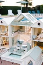 Handcrafted wooden dollhouse with miniature furniture and details, displayed in a minimal setting.