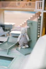 Handcrafted wooden dollhouse with miniature furniture and details, displayed in a minimal setting.