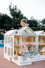 Handcrafted wooden dollhouse with miniature furniture and details, displayed in a minimal setting.