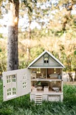 Victorian-style handcrafted white wooden dollhouse by Little Forest Animals, photographed outdoors on green grass in natural light.