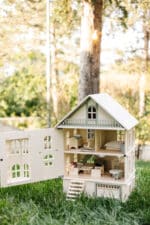 Victorian-style handcrafted white wooden dollhouse by Little Forest Animals, photographed outdoors on green grass in natural light.
