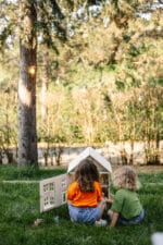 Victorian-style handcrafted white wooden dollhouse by Little Forest Animals, photographed outdoors on green grass in natural light.