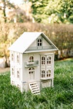 Victorian-style handcrafted white wooden dollhouse by Little Forest Animals, photographed outdoors on green grass in natural light.