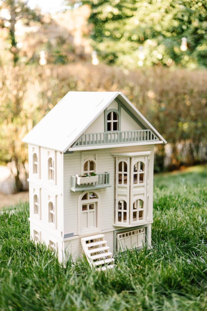 Victorian-style handcrafted white wooden dollhouse by Little Forest Animals, photographed outdoors on green grass in natural light.