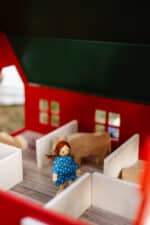 Handcrafted red wooden barn-style dollhouse with green roof, designed by Little Forest Animals for sustainable and imaginative play.