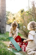 Handcrafted red wooden barn-style dollhouse with green roof, designed by Little Forest Animals for sustainable and imaginative play.