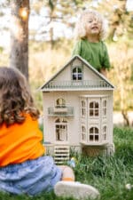Victorian-style handcrafted white wooden dollhouse by Little Forest Animals, photographed outdoors on green grass in natural light.
