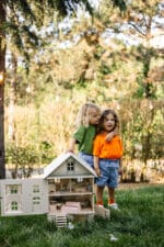 Victorian-style handcrafted white wooden dollhouse by Little Forest Animals, photographed outdoors on green grass in natural light.