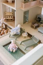 Handcrafted wooden dollhouse with miniature furniture and details, displayed in a minimal setting.