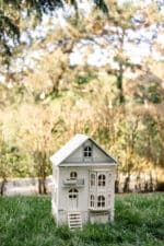 Victorian-style handcrafted white wooden dollhouse by Little Forest Animals, photographed outdoors on green grass in natural light.