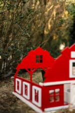 Handcrafted red wooden barn-style dollhouse with green roof, designed by Little Forest Animals for sustainable and imaginative play.