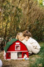 Handcrafted red wooden barn-style dollhouse with green roof, designed by Little Forest Animals for sustainable and imaginative play.