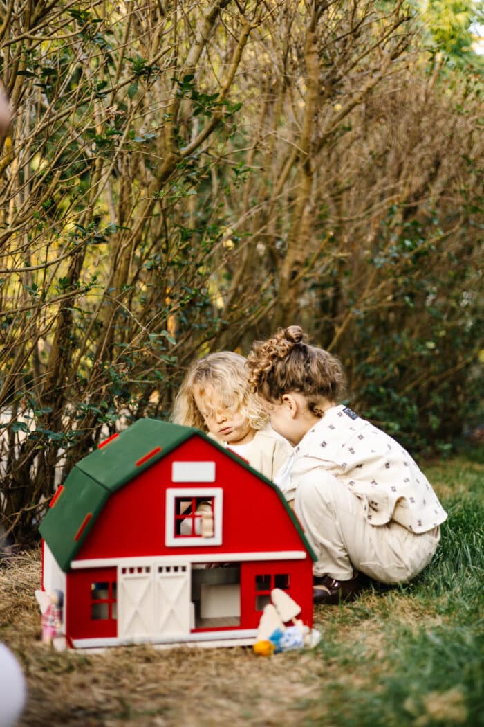 Handcrafted red wooden barn-style dollhouse with green roof, designed by Little Forest Animals for sustainable and imaginative play.