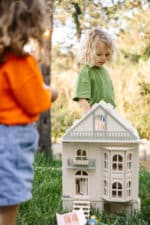 Victorian-style handcrafted white wooden dollhouse by Little Forest Animals, photographed outdoors on green grass in natural light.