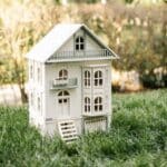 Victorian-style handcrafted white wooden dollhouse by Little Forest Animals, photographed outdoors on green grass in natural light.