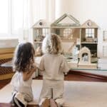 Handcrafted wooden dollhouse with miniature furniture and details, displayed in a minimal setting.