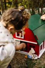 Handcrafted red wooden barn-style dollhouse with green roof, designed by Little Forest Animals for sustainable and imaginative play.