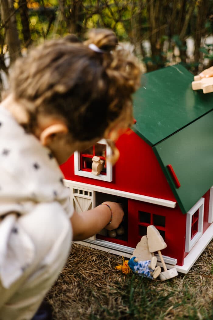 Handcrafted red wooden barn-style dollhouse with green roof, designed by Little Forest Animals for sustainable and imaginative play.