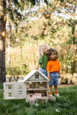 Victorian-style handcrafted white wooden dollhouse by Little Forest Animals, photographed outdoors on green grass in natural light.