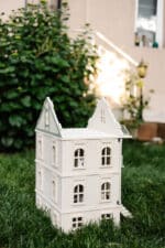 Victorian-style handcrafted white wooden dollhouse by Little Forest Animals, photographed outdoors on green grass in natural light.