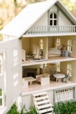 Victorian-style handcrafted white wooden dollhouse by Little Forest Animals, photographed outdoors on green grass in natural light.